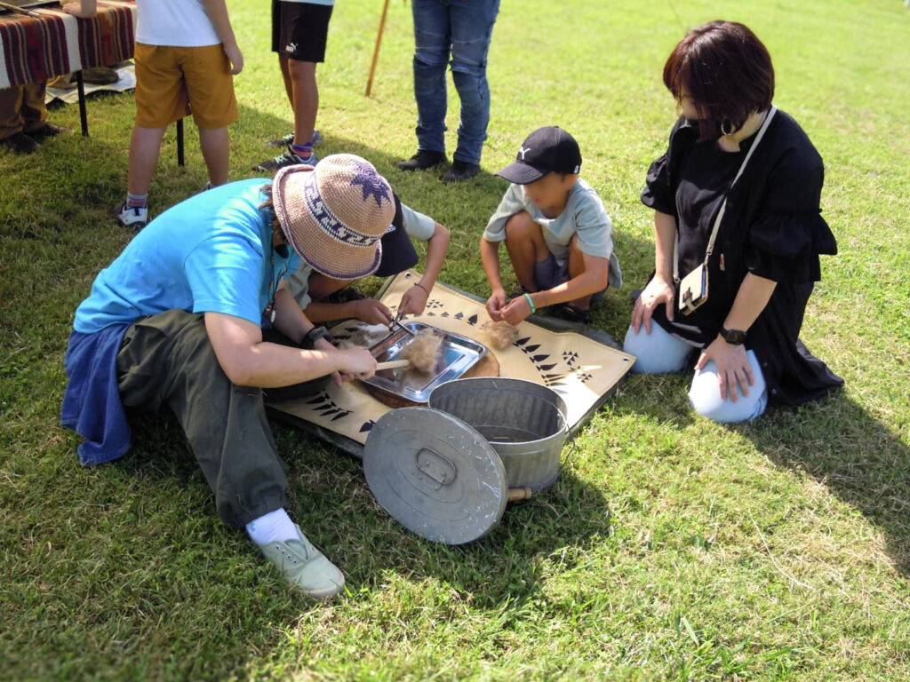 講師と一緒に火起こし体験に取り組む親子の様子